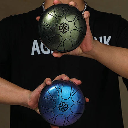 Deux steel tongue drums Sonora-Mundi noirs et bleus tenus par une personne, fond neutre.