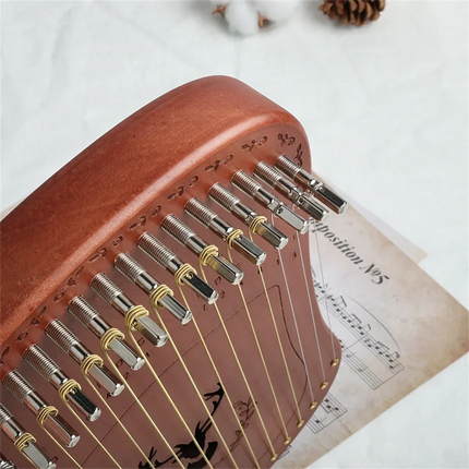 Détail d'une lyre en bois Sonora-Mundi avec cordes et partition musicale en fond.
