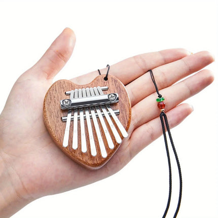 Mini kalimba en bois en forme de cœur Sonora-Mundi tenue dans une main, cordon noir et perles.